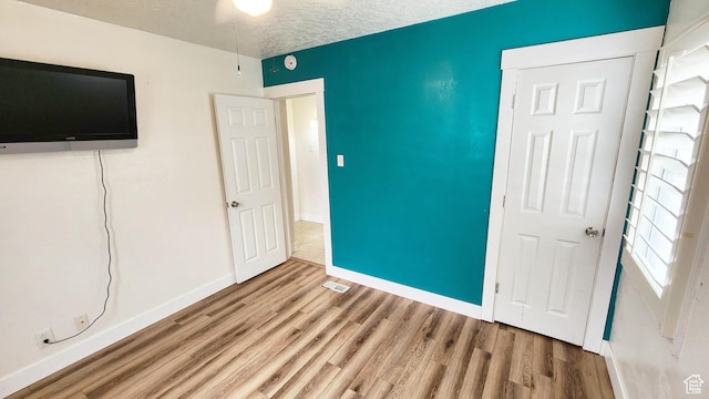 unfurnished bedroom featuring baseboards, visible vents, wood finished floors, and a textured ceiling