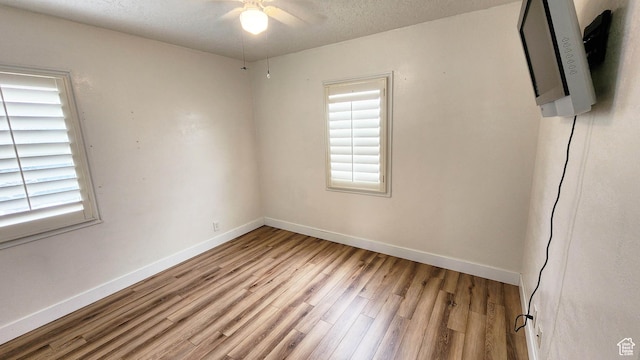 spare room with baseboards, a textured ceiling, light wood-style flooring, and a ceiling fan