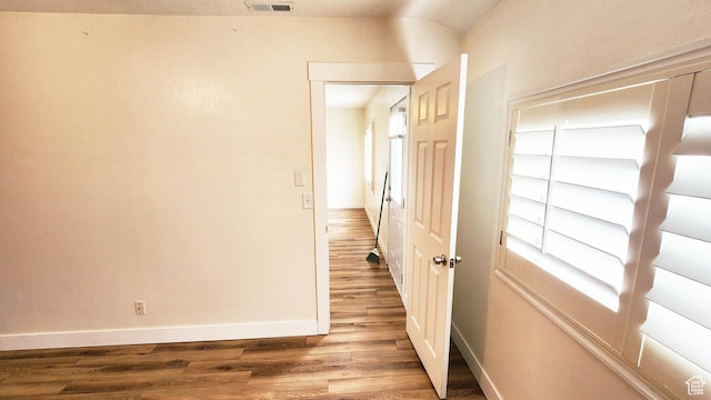 hallway featuring baseboards, visible vents, and wood finished floors
