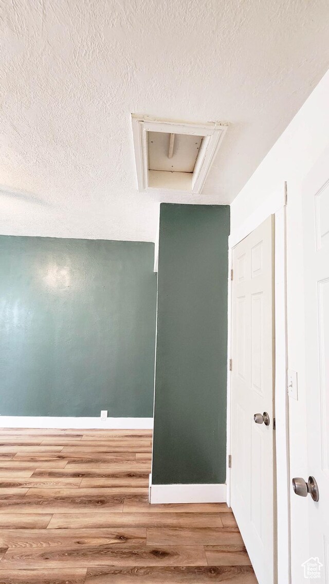 empty room with baseboards, wood finished floors, and a textured ceiling