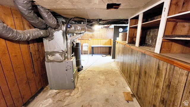 unfinished basement featuring water heater and wooden walls