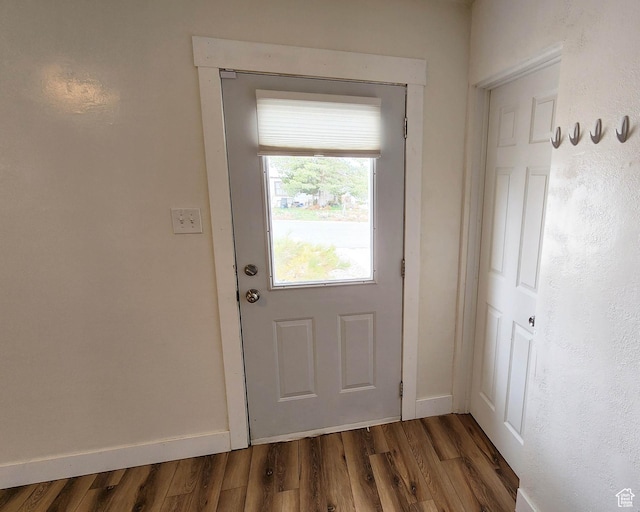 doorway to outside with baseboards and wood finished floors