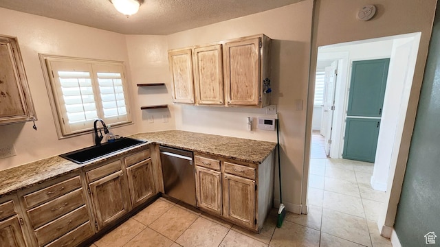 kitchen with light tile patterned floors, a sink, a textured ceiling, and stainless steel dishwasher