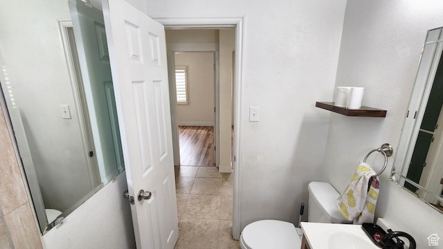 half bath featuring baseboards, toilet, and tile patterned flooring