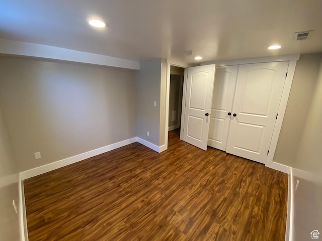 finished below grade area with baseboards, dark wood-style flooring, visible vents, and recessed lighting