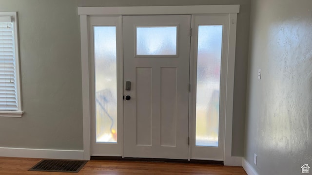 foyer entrance featuring wood finished floors, baseboards, and visible vents