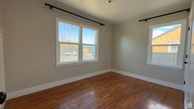 spare room with baseboards and dark wood-type flooring