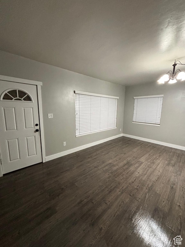 interior space with dark wood-type flooring, baseboards, and a chandelier
