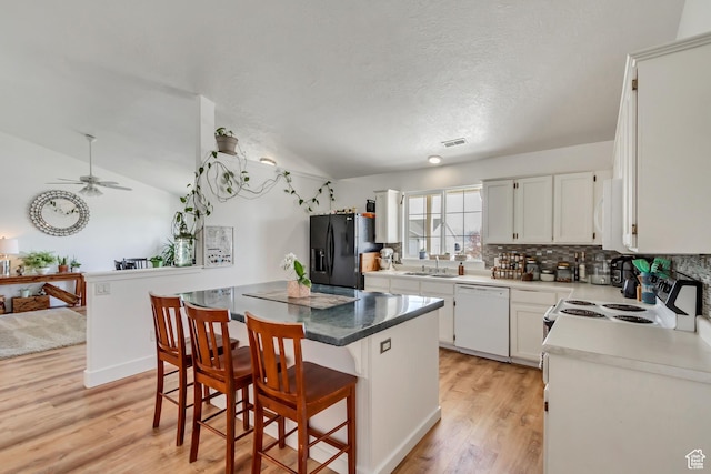 4103 S Sunrise Dr, Saratoga Springs, UT 84045 - kitchen with lofted ceiling, white appliances, a center island, light wood finished floors, and visible vents