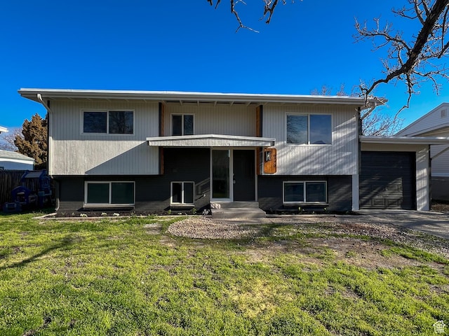rear view of house with a lawn, driveway, a garage, and entry steps