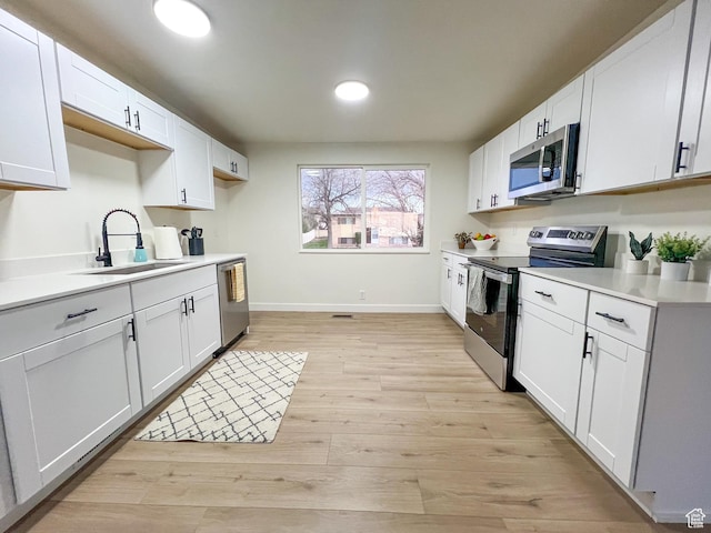 6770 W 3860 S, West Valley City, UT 84128 - kitchen featuring light countertops, a sink, light wood finished floors, stainless steel appliances, and white cabinets