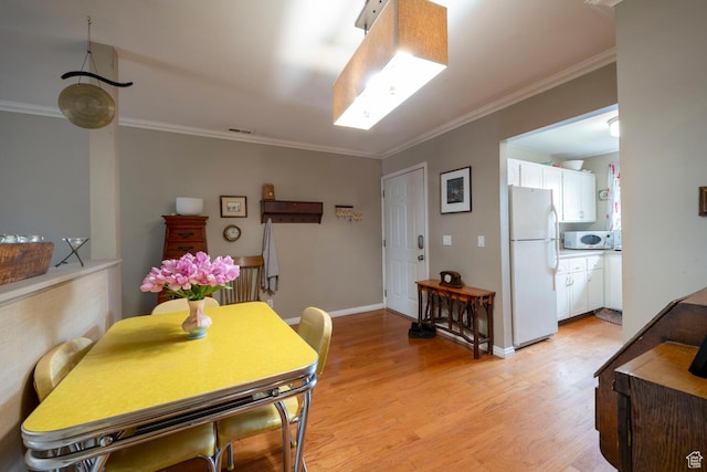 dining room featuring baseboards, visible vents, ornamental molding, and light wood-style flooring