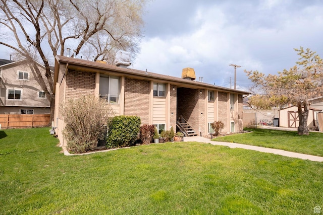 exterior space with a front lawn, an outdoor structure, fence, and brick siding