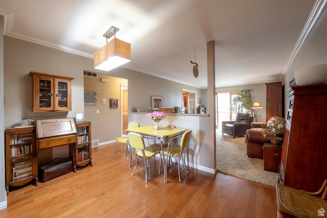 dining space with visible vents, light wood-style floors, and crown molding