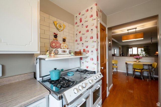 kitchen featuring light countertops, pendant lighting, double oven range, wood finished floors, and baseboards