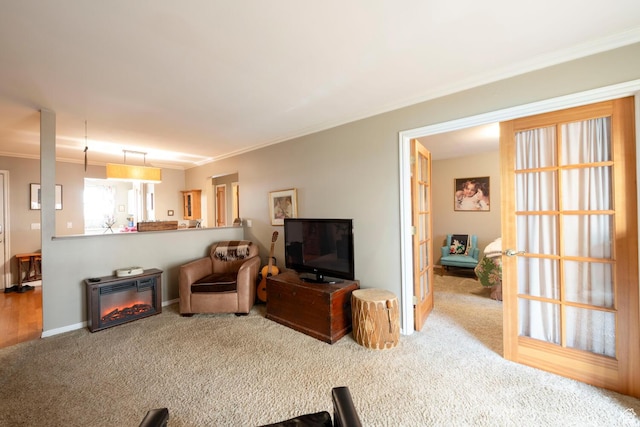living room featuring baseboards, crown molding, carpet floors, and a glass covered fireplace