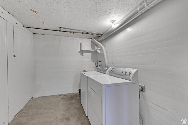 laundry area featuring laundry area, concrete block wall, and washer and clothes dryer