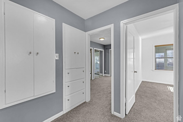 corridor featuring baseboards and carpet