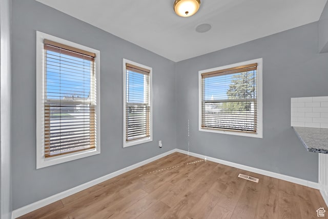 unfurnished room featuring light wood-type flooring, visible vents, and baseboards