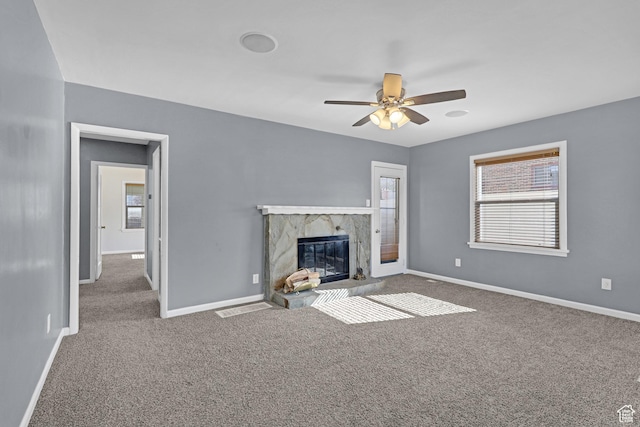 unfurnished living room with baseboards, visible vents, ceiling fan, a high end fireplace, and carpet
