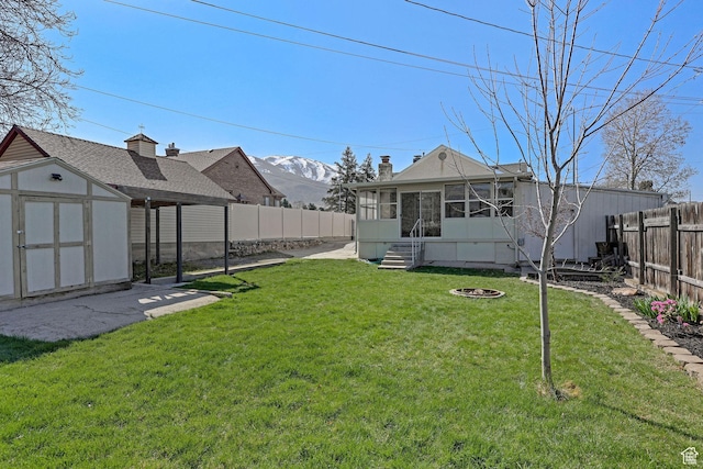 view of yard featuring a fenced backyard, an outdoor structure, a sunroom, and a storage unit
