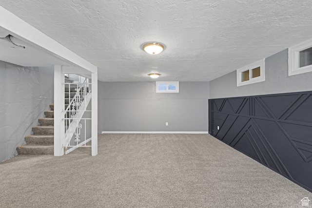 basement featuring stairs, carpet flooring, baseboards, and a textured ceiling
