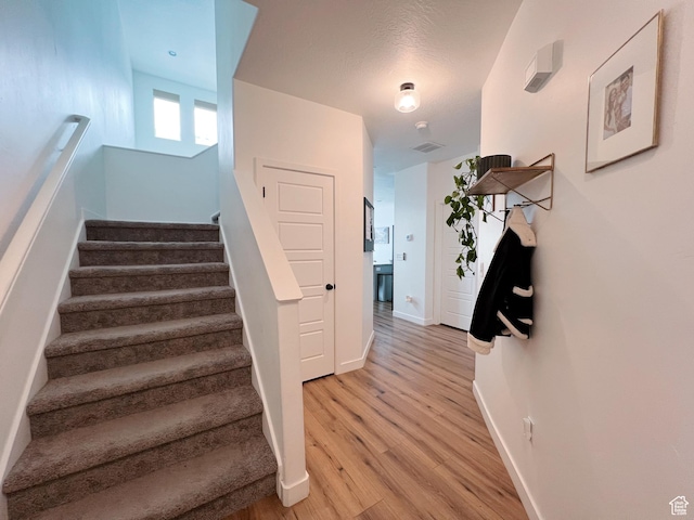 stairway featuring visible vents, baseboards, and wood finished floors