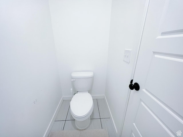 bathroom with toilet, baseboards, and tile patterned flooring