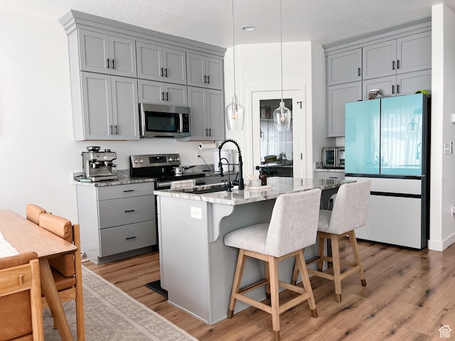 kitchen featuring light stone counters, gray cabinetry, and stainless steel appliances