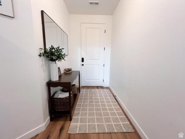 doorway featuring light wood-type flooring, baseboards, and visible vents