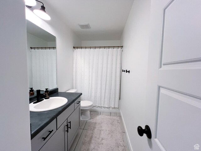 bathroom featuring toilet, vanity, baseboards, and a shower with curtain