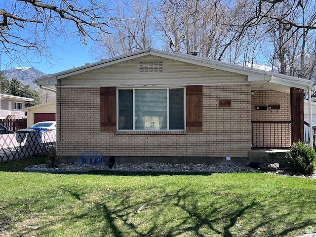 view of front of home featuring a garage, fence, a front lawn, brick siding, and a mountain view