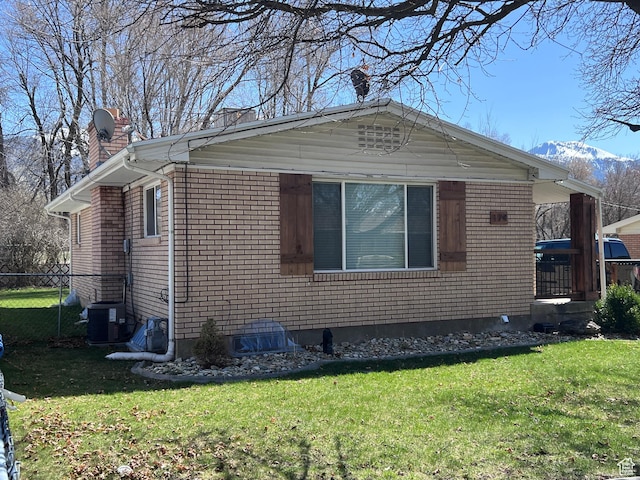 174 N 500 E, Logan, UT 84321 - view of home's exterior with central air condition unit, a chimney, brick siding, fence, and a lawn