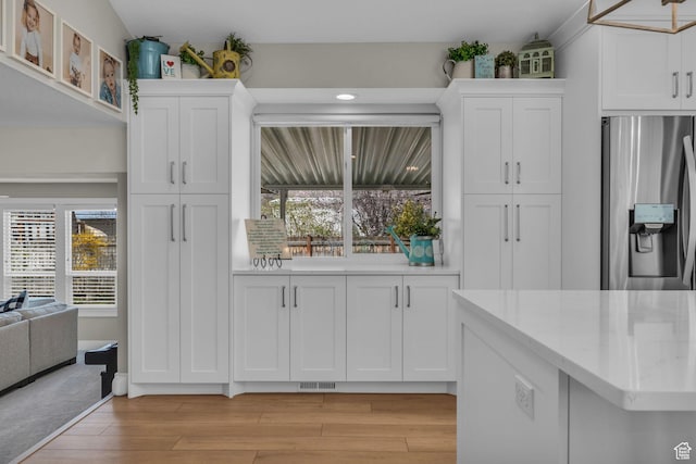 945 E Diana Way, Sandy, UT 84094 - kitchen with light wood-style floors, visible vents, stainless steel fridge, and white cabinets