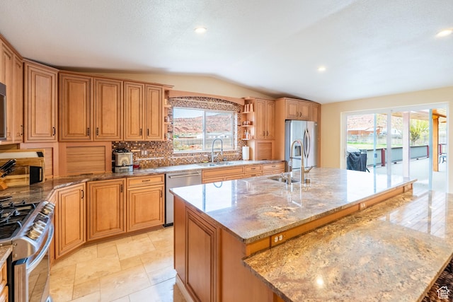 69 E Coronado Ln, Moab, UT 84532 - kitchen with light stone countertops, vaulted ceiling, appliances with stainless steel finishes, a kitchen island with sink, and a sink