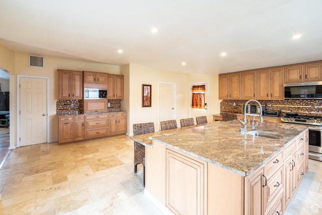 69 E Coronado Ln, Moab, UT 84532 - kitchen with visible vents, a sink, stainless steel appliances, decorative backsplash, and light stone counters