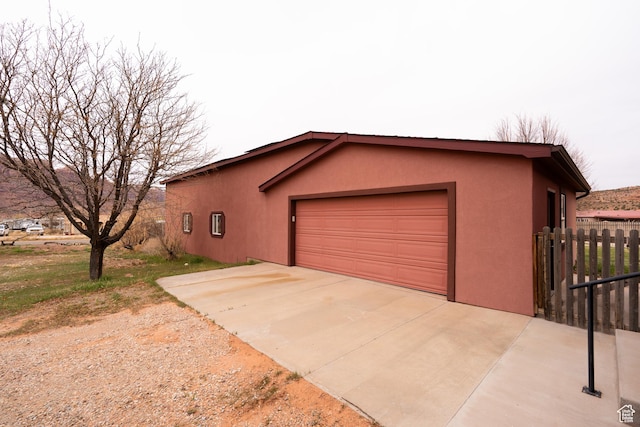 69 E Coronado Ln, Moab, UT 84532 - view of side of home featuring concrete driveway, fence, a garage, and stucco siding