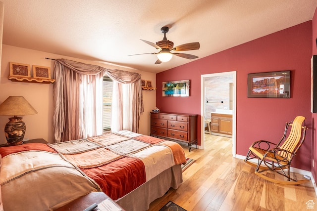 69 E Coronado Ln, Moab, UT 84532 - bedroom featuring baseboards, a textured ceiling, light wood finished floors, connected bathroom, and vaulted ceiling