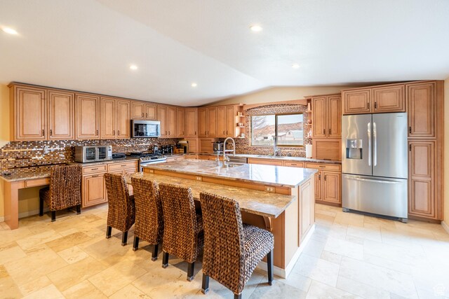 69 E Coronado Ln, Moab, UT 84532 - kitchen with light stone counters, an island with sink, lofted ceiling, stainless steel appliances, and a sink