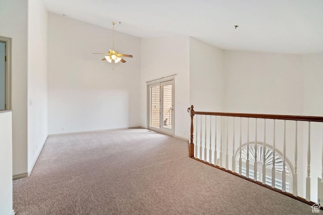 carpeted spare room with vaulted ceiling, a ceiling fan, and baseboards
