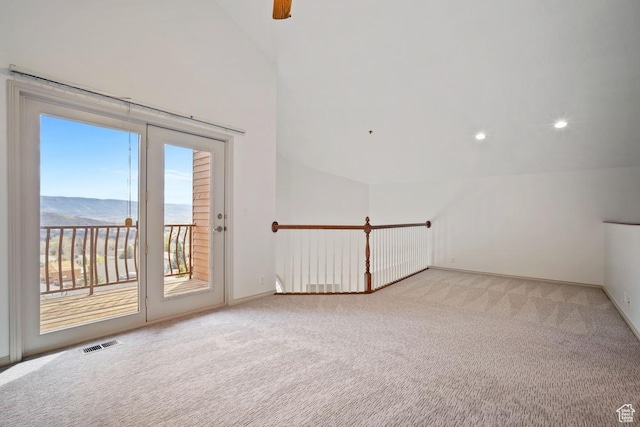 spare room with light carpet, lofted ceiling, visible vents, and baseboards