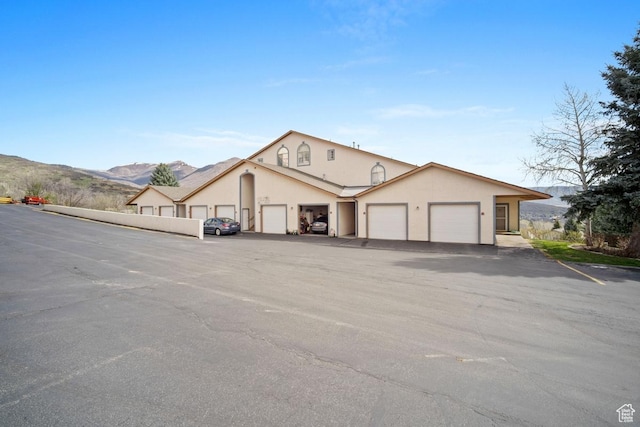 view of front facade featuring stucco siding, an attached garage, and a mountain view
