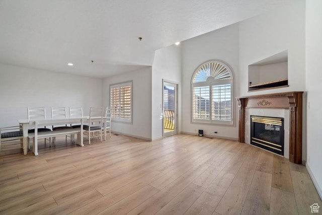 unfurnished living room featuring light wood finished floors, baseboards, a fireplace, and recessed lighting