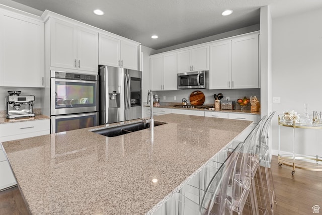 11534 S Rk Cv, South Jordan, UT 84095 - kitchen with stainless steel appliances, light wood-type flooring, a center island with sink, recessed lighting, and white cabinets