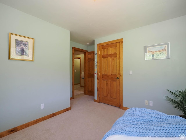bedroom with light colored carpet and baseboards