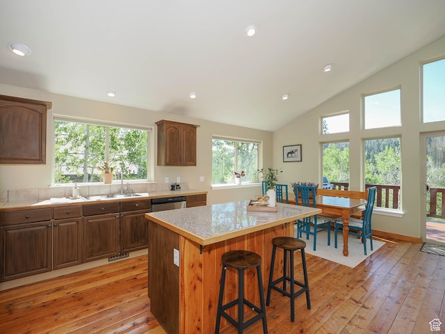 kitchen with a center island, light countertops, a kitchen bar, light wood finished floors, and dishwasher