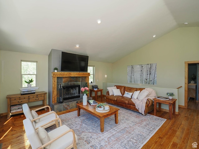 living room featuring a wealth of natural light, a tile fireplace, hardwood / wood-style floors, and vaulted ceiling