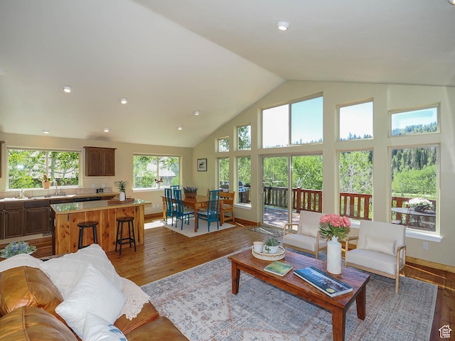 living room with high vaulted ceiling, recessed lighting, wood finished floors, and baseboards