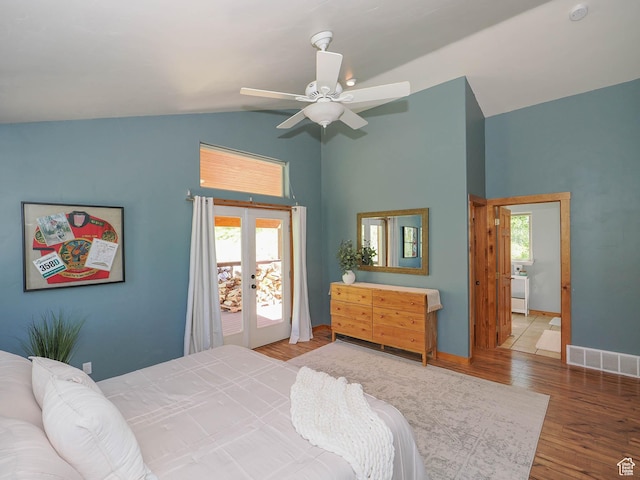 bedroom with visible vents, multiple windows, vaulted ceiling, and wood finished floors