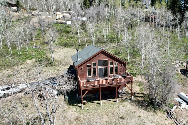 rear view of property with a view of trees, a wooden deck, and metal roof